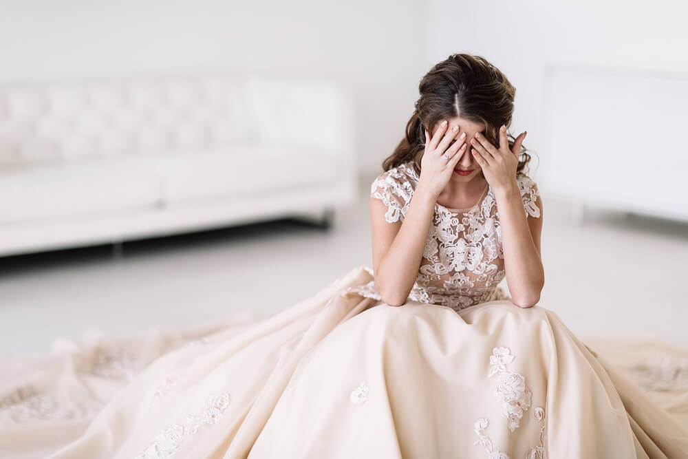 the bride sits in a white room and is sad. Natural light. covers your eyes